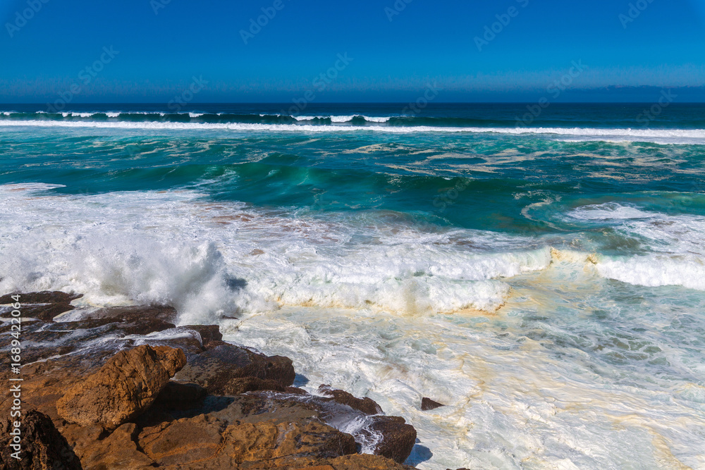 Fototapeta premium Powerful waves crash against rugged coastal rocks