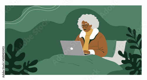 Elderly Black woman focused on her laptop while relaxing in bed, illustrating remote work, online learning, and modern senior living.