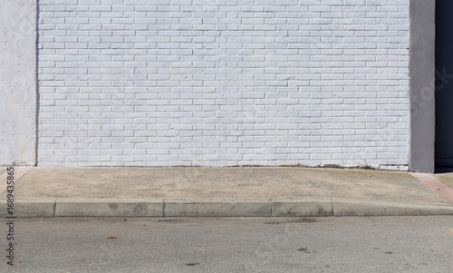 Wallpaper Mural White painted brick wall at the roadside with concrete sidewalk and road in front. Background for copy space. Torontodigital.ca