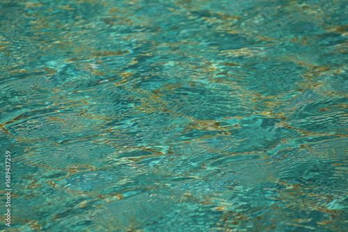 Pool with clear water is lined with blue-green tiles. Calm water is reflected in tile and creates serene atmosphere