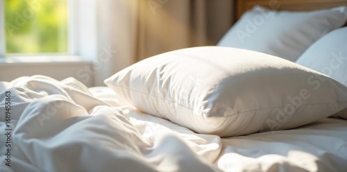 Soft, fluffy pillow resting on a crisp white bedsheet, ready for a peaceful night's sleep  Sunlight streams in, illuminating the plush texture ,  peaceful,  cotton,  sleep