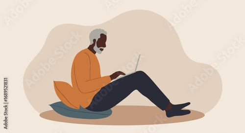 Mature Black man comfortably uses a laptop, sitting on the floor with a pillow. Represents remote work, online learning, or leisurely digital engagement at home.