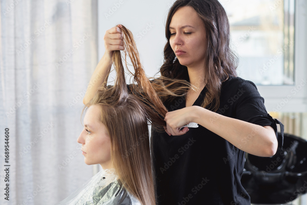 Fototapeta premium Close up of hairdressers hands drying long blond hair with blow dryer and round brush