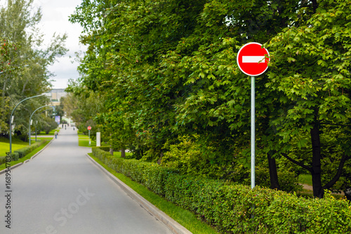  a road sign prohibiting passage stands in front of a pedestrian zone. travel prohibited. pedestrian area in the park. red prohibition sign