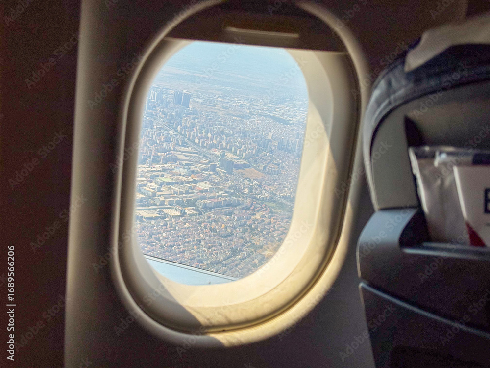 Fototapeta premium View from airplane window showing city and aircraft outside. Travel, aviation, and mobility symbolizing journey, tourism, and modern transportation.