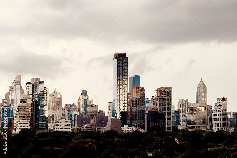 Obraz premium A modern city with towering skyscrapers under a dramatic cloudy skyThe sepia tone effect creates an urban and artistic atmosphere perfect for business architecture and cityscape themes Here in Bangkok