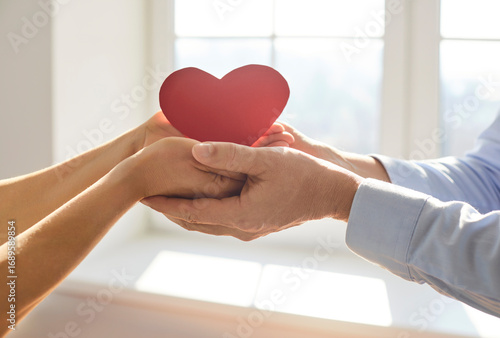 Quadro em tela Two pairs of hands gently holding red paper heart together