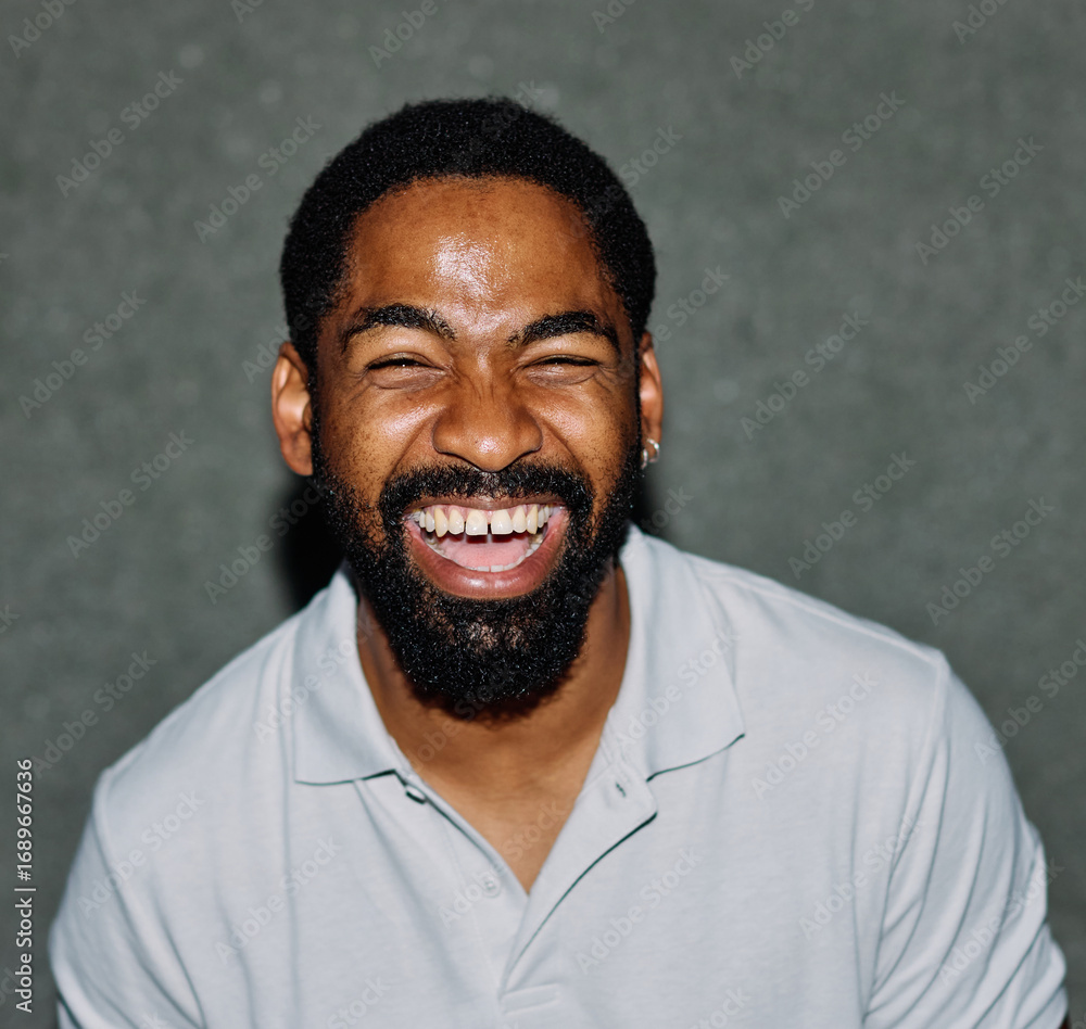 Obraz premium A portrait of young happy black man posing by a gray wall in the street outdoors