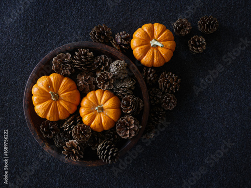 Overhead view of pumpkins and acorns flat lay on a dark textured surface for autumnal equinox day marking the beginning of Fall season. Fall background with copy space.