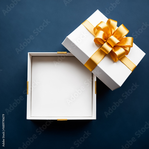 a clean white open gift box with a bright golden bow and ribbon, creating a striking contrast against a deep blue background, viewed from above.