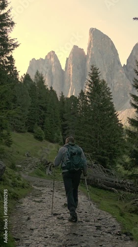 Vertical screen of hiker ascending mountain path at sunset in Dolomites, Italy Silhouette of trekking man on stony alpine trail during evening 