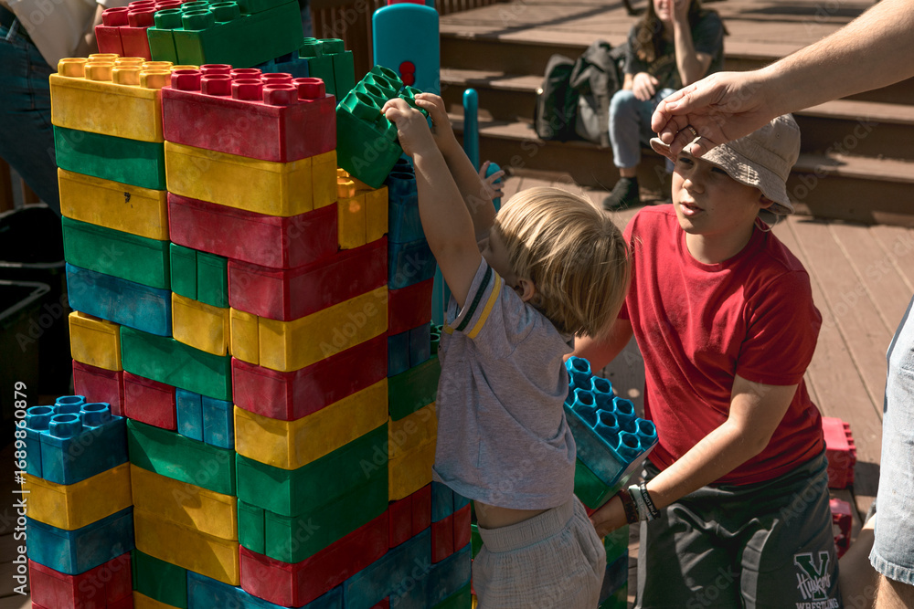 Obraz premium Child playing with big LEGO bricks outside, creative activity and fun learning