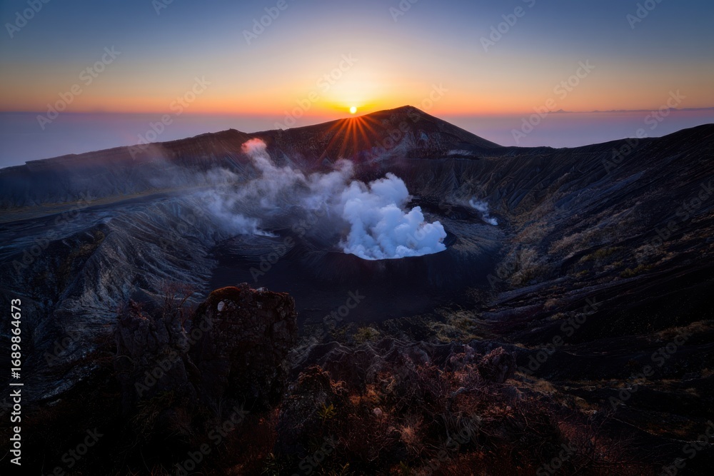 Fototapeta premium Active volcano erupting steam at sunrise with dramatic sky