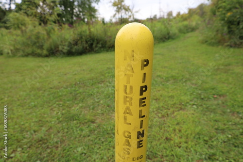 Natural gas pipeline warning post in nature area with green field