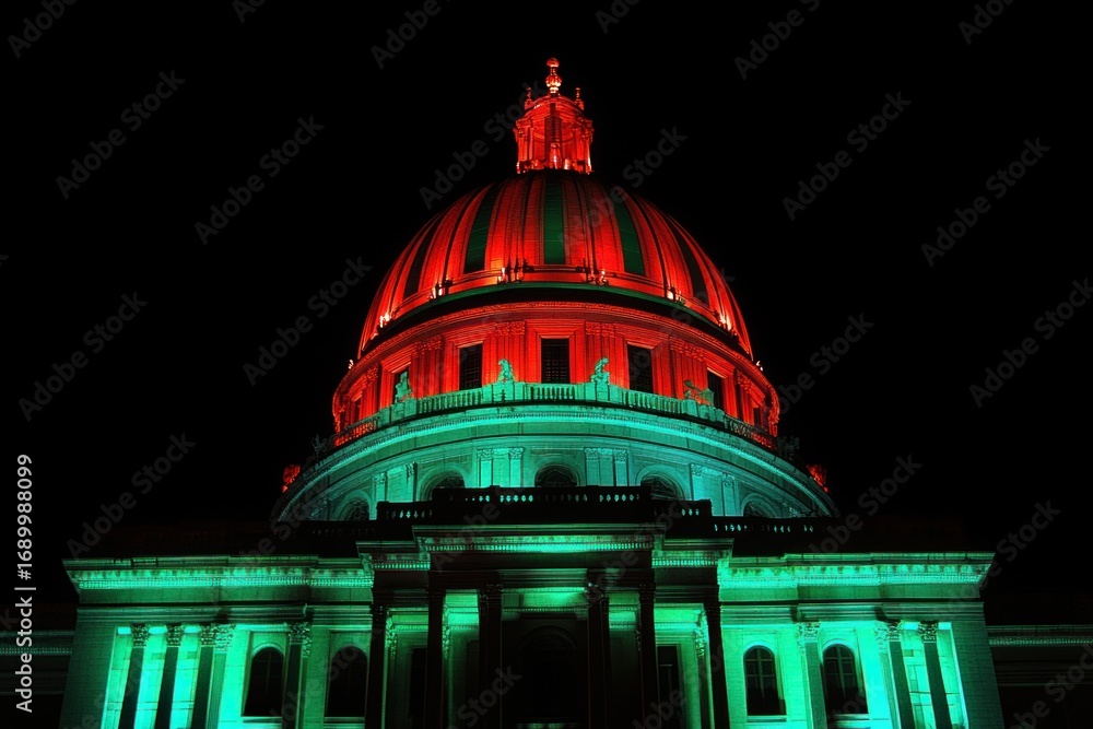 Obraz premium Illuminated large domed building at night with vibrant red and green lighting highlighting its architectural details against a dark sky