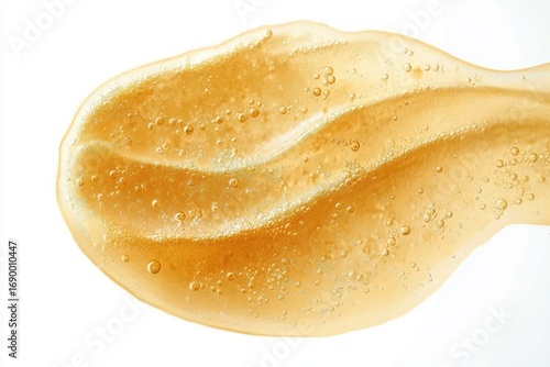 Close-up of a translucent golden gel with suspended bubbles against a white background