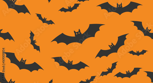 Spooky halloween orange background with silhouetted bats flying all over the place