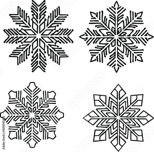 Four snowflakes with intricate geometric patterns arranged on a white surface, creating a simple and elegant wintery scene.