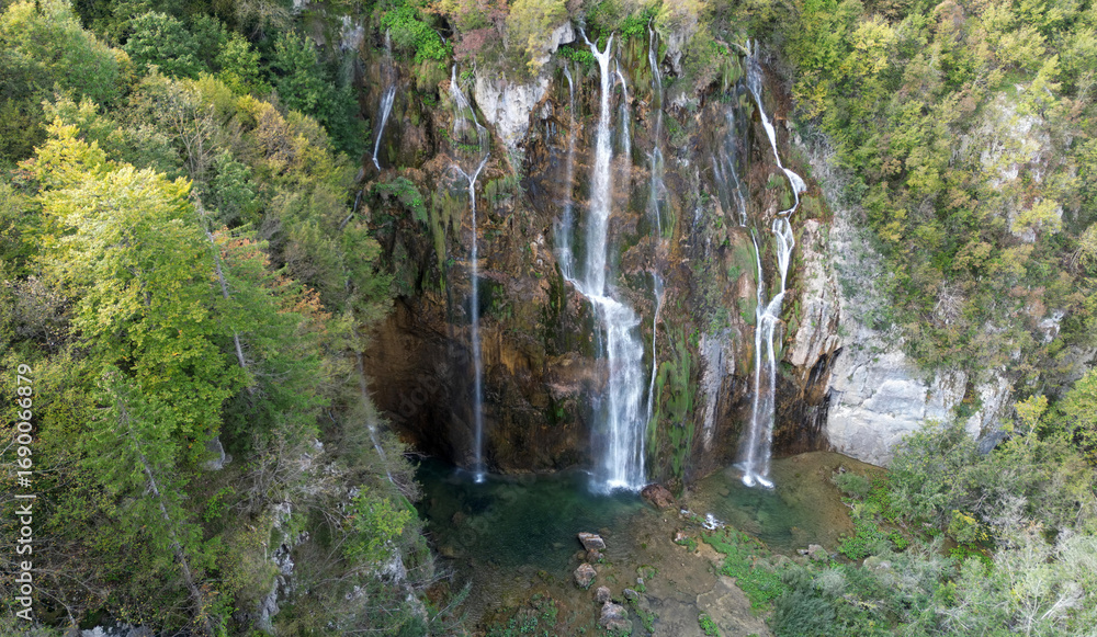 Fototapeta premium Beauty in summer nature, amazing waterfall in forest. Waterfall and pond. Panoramic beautiful deep forest waterfall. Beautiful view to waterfalls with green forest. The tranquil waters of waterfalls.