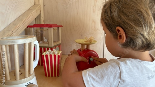 Obraz na plátně Child playing with wooden toy kitchen, popcorn and scale