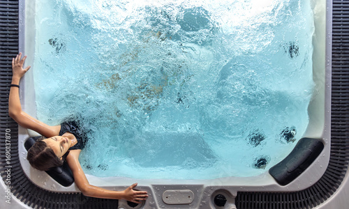 Girl in spa hot tub seen from above with bubbling water. Overhead view.