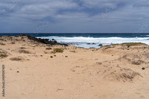 Wallpaper Mural A serene beach scene with sandy dunes, volcanic rocks, and the vast ocean under a cloudy sky, capturing the beauty of La Graciosa. Torontodigital.ca