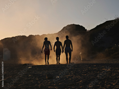 Fototapeta Grupo de bañistas levantan polvo de la arena de la playa de Marbella al atardece