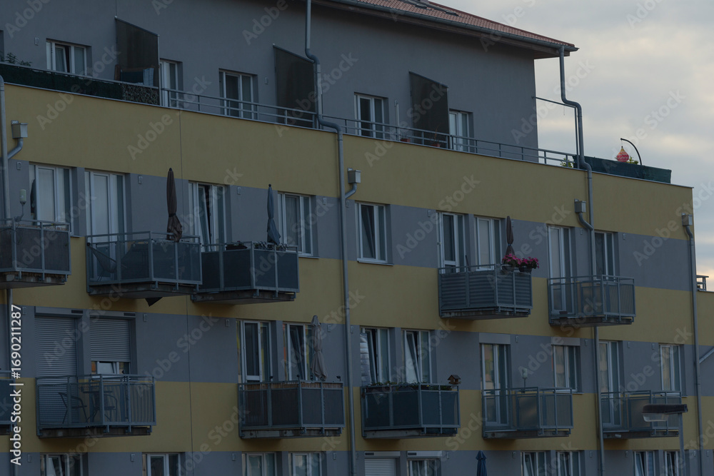 Obraz premium Contemporary apartment building features multiple balconies and air conditioning units, showcasing urban living in a modern setting.