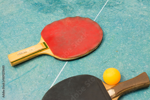 Ping pong paddles and ball on retro  blue wooden background. Rackets ruined by time