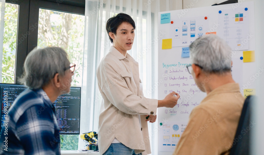 Obraz premium senior programmer bootcamlp,Asian young instructor guides senior learners through a programming on whiteboard, highlighting algorithm thinking and simple code exercises