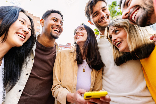 Happy group of friends using having fun using mobile phone at city street. Social media and youth concept