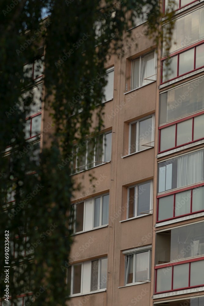 Fototapeta premium A close-up view of a modern apartment building showcasing large windows and a touch of greenery in the foreground, emphasizing urban living.