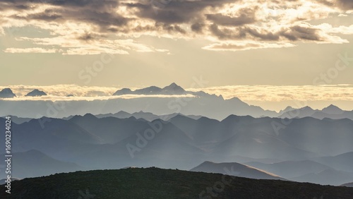 Layered mountain landscape with golden clouds at sunset