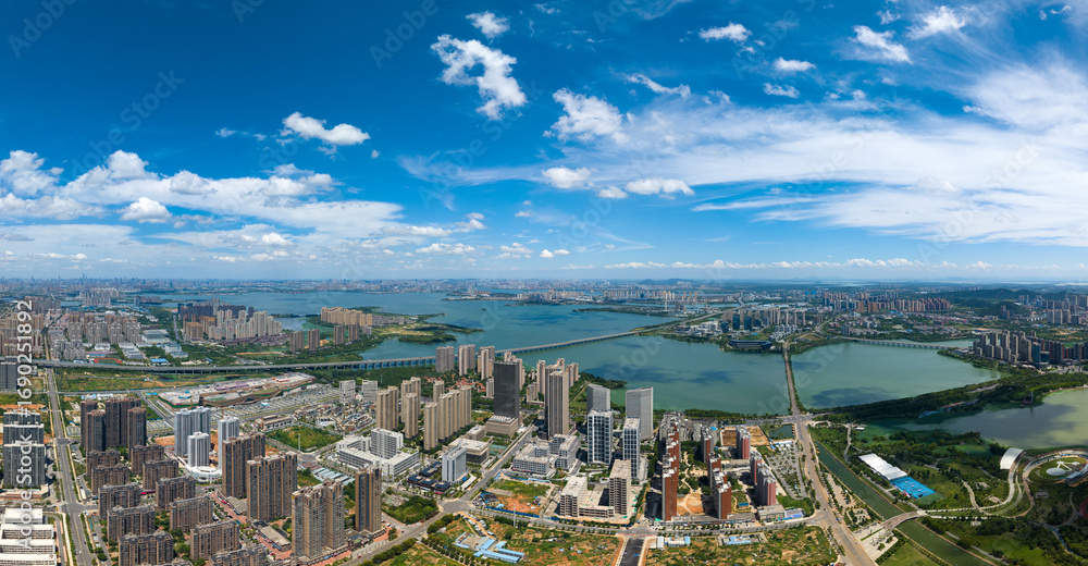 Fototapeta premium Jiangxia Tangxun Lake landscape shows city buildings reaching the horizon under a bright blue sky.