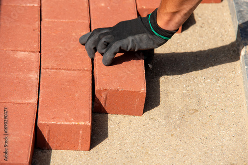 Φωτογραφία Bricklaying process on a sunny day with a worker placing red bricks on a sandy s