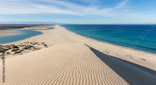 Vast Sand Dunes Meeting the Ocean Under a Blue Sky.