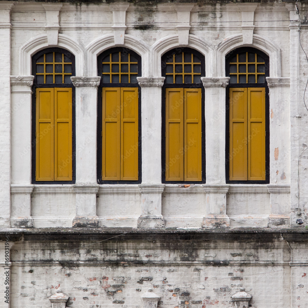 Obraz premium Yellow wooden windows closed with white rustic walls.