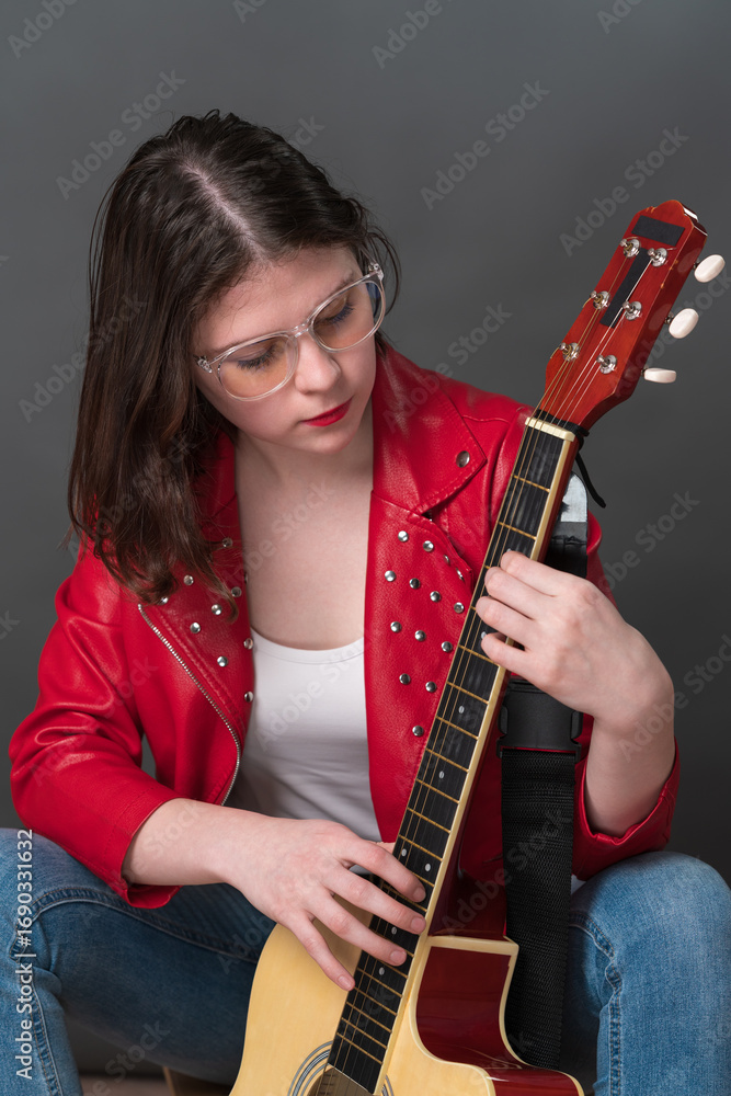 Φωτογραφία Female guitarist and musician in process of tuning her acoustic guitar, holding