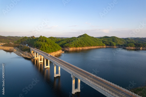 Wallpaper Mural Scenic bridge spans the calm Danjiangkou Reservoir in China, surrounded by lush green mountains under a bright blue sky. Torontodigital.ca