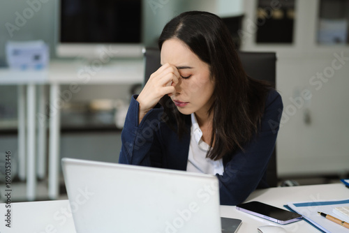 Tired asian businesswoman with headache at office, feeling sick at work.