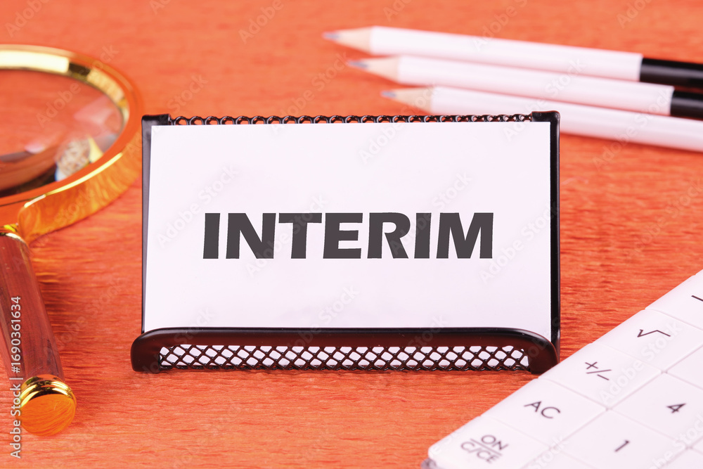 Ταπετσαρία Interim writing on a white business card, close-up in front of an orange backgro