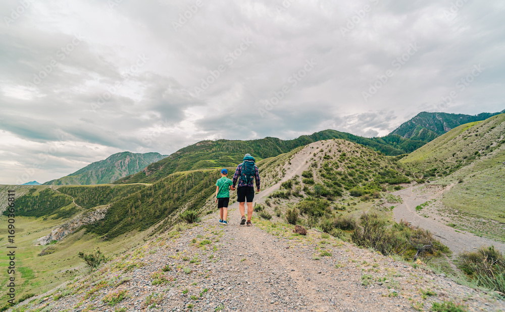 Fototapeta premium Father and son walks on trail. Stunning countryside vistas to serene hilltop trails, there are countless destinations that cater to travelers seeking adventure and solitude.