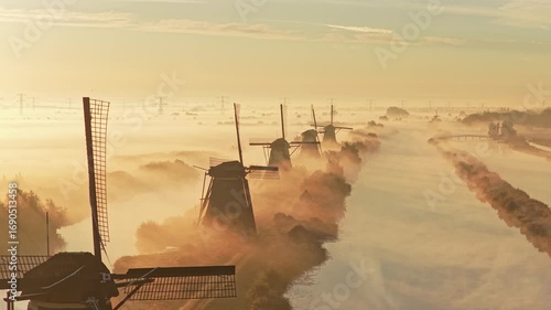 Cinematic drone flight above Kinderdijk heritage windmills in soft fog, Netherlands