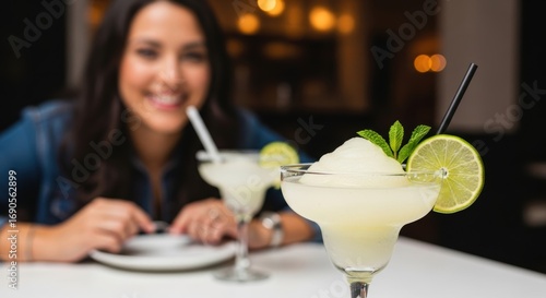 Smiling hispanic female enjoying margarita drink at table in a bar setting