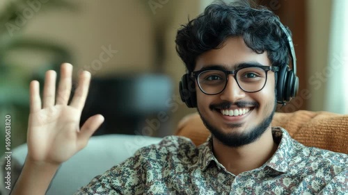 A smiling Indian man wearing headphones and waving at the camera, indicating he is ready to entertain with music or audio content.