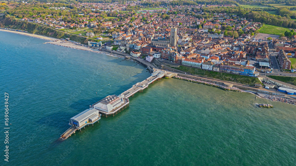 Fototapeta premium Aerial panoramic drone view of Cromer pier and the coastal town. Turquoise North Sea and the promenade. North Norfolk, England, UK 