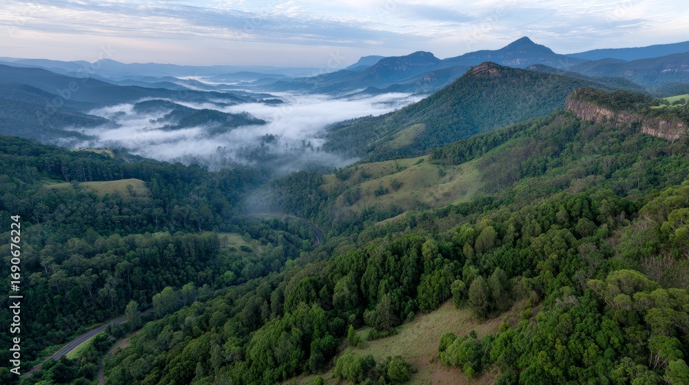 Obraz premium Misty mountain valley at dawn with lush green forests, rolling hills, soft pastel clouds, and an ethereal serene atmosphere, aerial view, copy space on the right