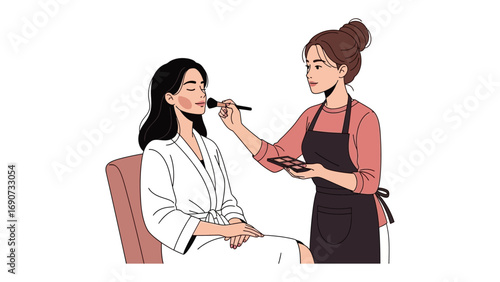 Professional makeup artist applying foundation to a young woman sitting in a chair wearing a white robe in a studio setting
