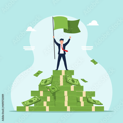 Businessman standing on a huge pile of money holding a green flag victorious achievement business success and financial growth concept