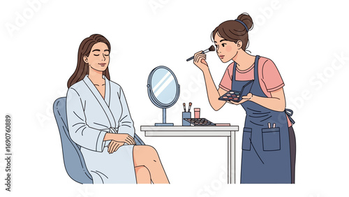 Young woman in a white robe receives makeup application from a professional makeup artist at a vanity table with a mirror
